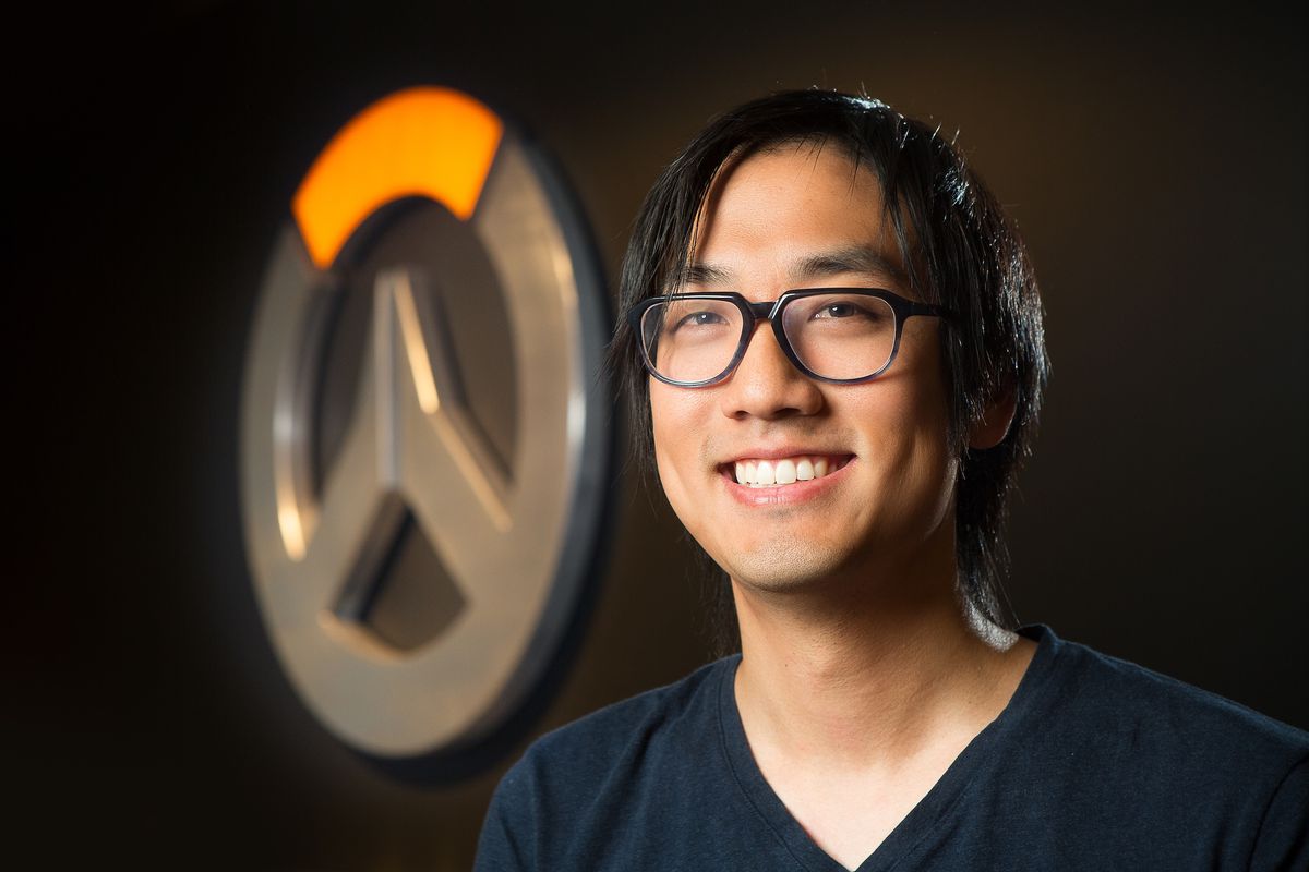 Una fotografía de Michael Chu frente al logo de Overwatch