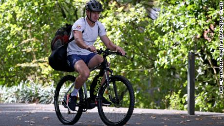 El jugador de rugby neozelandés Beauden Barrett llega en su bicicleta para patear el entrenamiento de forma aislada.