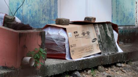 El ataúd que contiene el cuerpo de una persona que probablemente murió de Covid-19, yace envuelto en papel de aluminio y cartón frente al bloque de pisos familiares en Guayaquil el 2 de abril.