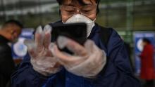 Un pasajero que usa una máscara facial usa un teléfono inteligente para escanear el código QR de salud de la ciudad de Wuhan antes de ingresar al aeropuerto de Tianhe.