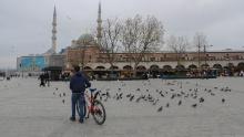 Un hombre con una bicicleta rodeado de palomas en la plaza Yenicami casi vacía, en el Bazar de las Especias en Estambul, Turquía, durante un bloqueo de fin de semana.