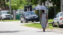Una mujer usa un paraguas para protegerse de la sombra cuando hace un día caluroso en Miami.