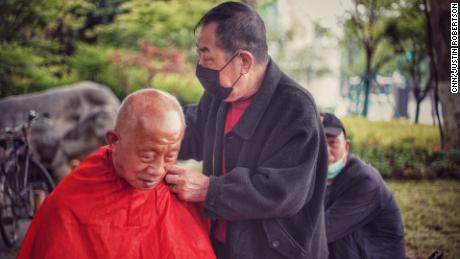 El hombre es afeitado en un barbero al aire libre en el parque Wuhan el 23 de abril.