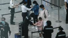 Los pasajeros reciben pulseras de cuarentena que siguen el 19 de marzo en el aeropuerto internacional de Hong Kong.