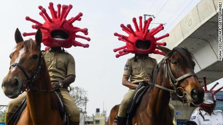 El personal de la policía en cascos motivados por coronavirus monta caballos, participando en una campaña de sensibilización en Secunderabad, una ciudad asociada de Hyderabad, el 2 de abril de 2020. 
