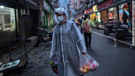 Una persona que usa una máscara facial como un medio para prevenir la propagación del nuevo coronavirus COVID-19, el 20 de abril, lleva víveres en el distrito de Wuhan del centro de Hubei, China.