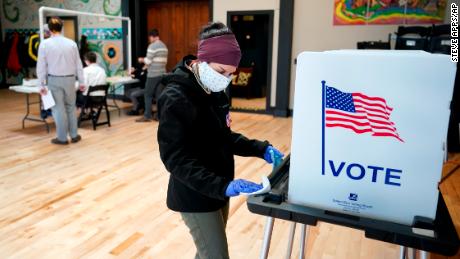 Un trabajador electoral de Wisconsin limpia la cabina de votación después de usarla el 7 de abril en Madison. El estado celebró una elección mientras ordenaba en casa. 