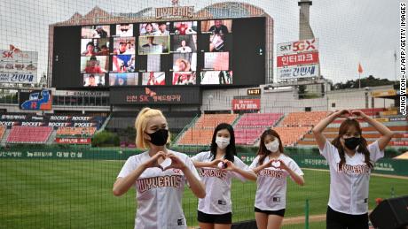 Las animadoras posan frente a una gran pantalla en la que los fanáticos del béisbol animan en sus hogares durante el partido inaugural de la nueva temporada de béisbol de Corea del Sur entre SK Wyverns y Hanwha Eagles en el estadio de béisbol Munhak en Incheon el martes.