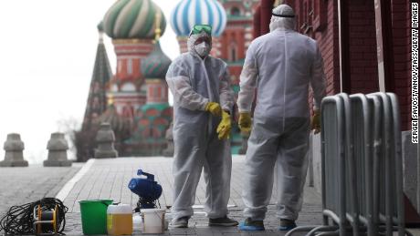 Personas en equipos de protección desinfectando la Plaza Roja en Moscú.