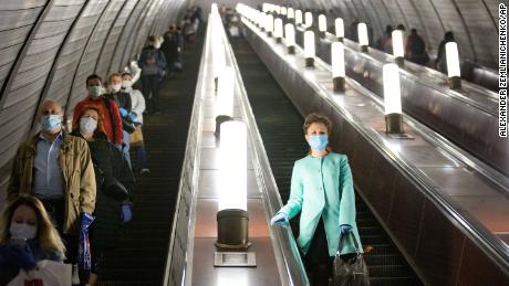 El martes, personas con máscaras y guantes en la escalera mecánica del metro de Moscú.