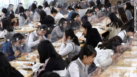 Los estudiantes mayores cenan en mesas equipadas con barreras de plástico para evitar la posible propagación del coronavirus en la cantina de la escuela secundaria Jeonmin en Daejeon, Corea del Sur, el miércoles 20 de mayo de 2020.