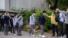 Los estudiantes con máscaras faciales se someten a un control de temperatura a su llegada a Keongbok High School en Seúl, 20 de mayo de 2020.