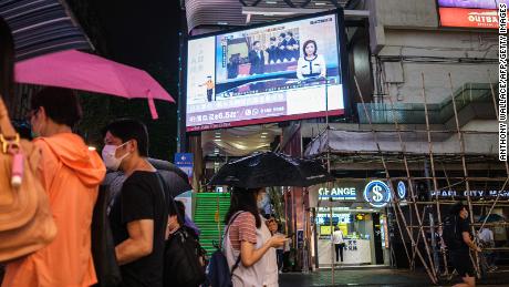 Los peatones pasean bajo una pantalla de televisión de Hong Kong el 21 de mayo de 2020, mostrando una transmisión televisiva desde Beijing del presidente chino Xi Jinping (C) en una conferencia de consulta política china.