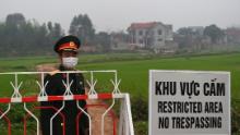 Un oficial del ejército vietnamita se encuentra junto a un cartel que advierte sobre el bloqueo del municipio de Son Loi en la provincia de Vinh Phuc el 20 de febrero.