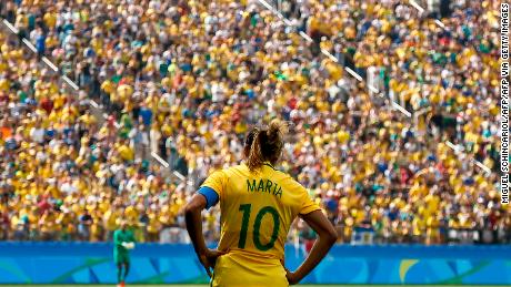 La jugadora brasileña Marta está parada frente a una multitud brasileña.