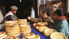 Uighur vende pan plano tradicional a mujeres que compran en la calle Xinjiang en Beijing en 1999.